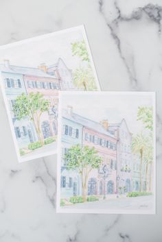 two watercolor paintings of buildings on a marble surface