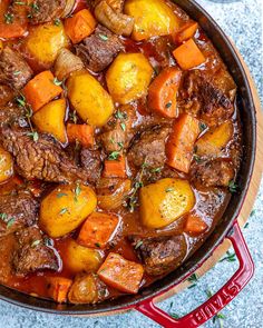 beef stew with carrots and potatoes in a red pot