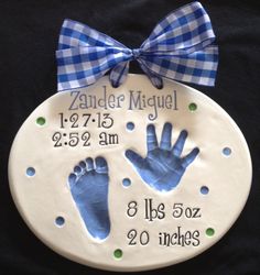 a baby's hand and foot print on a ceramic plaque with a blue bow