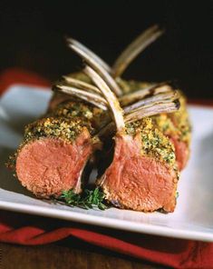 a piece of meat on a white plate with silver fork and garnishes