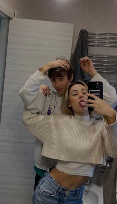 two people taking a selfie in a bathroom mirror with their hands on their heads