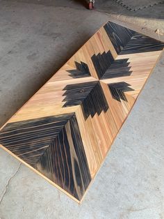 a wooden table with black and brown designs on it's sides, sitting in a garage