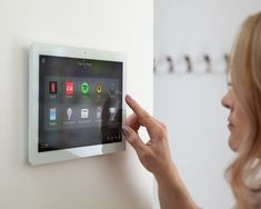 a woman is touching the buttons on a wall mounted touch screen