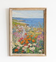 a painting hanging on the wall next to a white wall with flowers in front of it