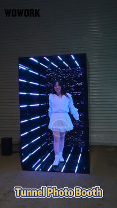 a woman standing in front of a large screen with lights on it's sides