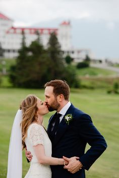 a bride and groom kissing in front of a golf course with the hotel behind them