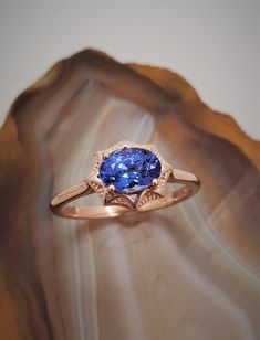 CJ72056TNZ Rose gold tanzanite ring. 14k rose gold east-west style ring with Art Deco elements. The ring is set with a beautiful 1.05ct Tanzanite. The gemstone is 7x5mm. Currently the ring is size 6.75, but we will resize at no extra charge. Please specify ring size if resizing is needed. Gold And Blue Tanzanite Wedding Ring Women, Luxury Amethyst Tanzanite Ring In Fine Jewelry Style, Luxury Tanzanite Sapphire Ring With Rose Cut Diamonds, Luxury Amethyst Tanzanite Ring Fine Jewelry, Tanzanite Rings, Art Deco Elements, Retail Jewelry, Tanzanite Ring, Purple Band