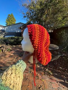 a woman's head wearing an orange and red knitted hat