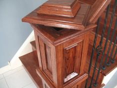 a wooden cabinet sitting on top of a white tiled floor next to a stair case