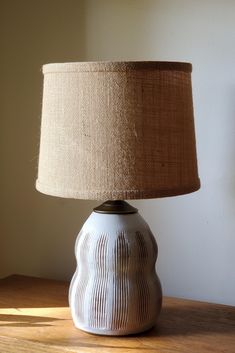 a lamp that is sitting on top of a wooden table next to a white wall