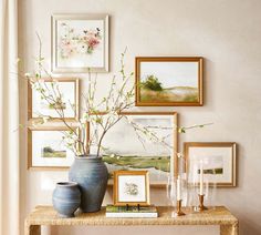 a table with vases and pictures on the wall