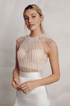 a woman in a white dress posing for the camera with her hand on her hip