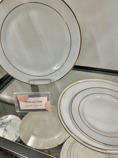 white and gold plates are on display in a glass case with a label that reads write - me - gold