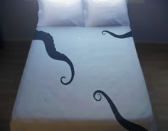 a bed with two white pillows on top of it and an octopus drawn on the pillow