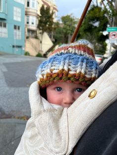 a small child wearing a knitted hat and holding on to the back of a car seat