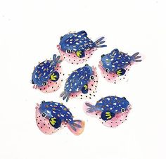 five blue and pink fish sitting next to each other on top of a white surface