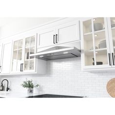 a kitchen with white cabinets and black counter tops is pictured in this image, there are plates on the stove