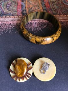 "Marbled BAKELITE Bangle and Artisan French GALALITH Clip-on Earrings Vintage 1940s Bakelite bangle and matching French galalith clip-on earrings. Although the bangle and earrings originally do not belong to each other they make a really nice set. The centerpart of the earrings wonderfully resembles the colors and paterning of the marbled bakelite of the bangle. Bangle measures 2 5/8 (6.6cm) in diameter and is 3/4\" wide. The French galalith earrings, measure 1 3/8\" in diameter, the fine workin Vintage Collectible Bangle Jewelry, Retro Metal Bangle Jewelry, Handmade Brass Art Deco Jewelry, Collectible Art Deco Bangle Jewelry, Vintage Bakelite Bangle, Bakelite Bangles, Spider Earrings, Vintage Jewelry Sets, Cat Brooch