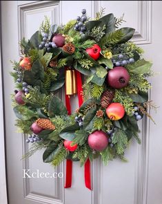 a christmas wreath on the front door with pine cones, berries and evergreens hanging from it