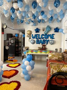 blue and white balloons are hanging from the ceiling in front of a welcome baby sign