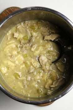 a pot filled with soup sitting on top of a white counter next to a wooden spoon