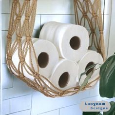 there are four rolls of toilet paper hanging from the wall in this bathroom rack with rope