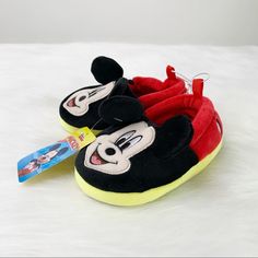 a pair of mickey mouse slippers on top of a white sheet with a toothbrush