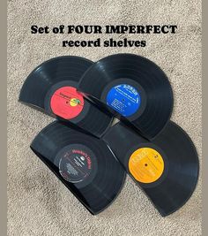 four different colored records sitting on top of a carpet with the words set of four imperfectect record sleeves