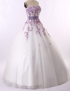 a white dress with purple flowers on the waist and bustle, is displayed in front of a mannequin