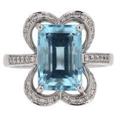 This sophisticated designer engagement ring presents a substantial 3.47 carat aquamarine gemstone, uniquely bejeweled with 44 glimmering diamonds. With a twist of contemporary fashion design, this ring harmoniously pays homage to the classic elegance of the Art Deco era. With its distinctive Alhambra quatrefoil design and deluxe workmanship, this wedding ring or right hand cocktail ring is sure to become a cherished heirloom. Photography © Bella Rosa Galleries Santa Barbara, CA Condition: Excellent Era: 2000s Year: Contemporary Metal: 18k White Gold Gemstone: Aquamarine Carat Weight: 3.47 Cut: Emerald Color: Vivid Sea Blue Clarity: Transparent Accent Diamonds: 44 Round Brilliant Cuts 0.27 carats total G-H Color, VS1-2 Clarity Ring Size: 6.5, sizing available Rise Above Finger: 8mm Ring Fac Heirloom Photography, Custom Ring Box, Gold Cocktail Ring, Gold Cocktail, Emerald Color, Engagement Ring Sizes, Aquamarine Gemstone, Garnet Rings, Gem Stone