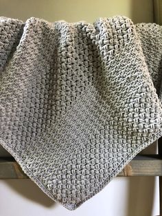 a crocheted blanket sitting on top of a wooden chair next to a window