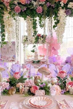 a table topped with lots of pink and white flowers next to a window filled with balloons