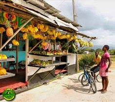 a woman standing next to a bike near a fruit stand