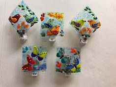 four colorful glass magnets with birds and sea creatures on them are hanging from the wall