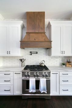 a stove top oven sitting inside of a kitchen next to white cabinets and wooden floors