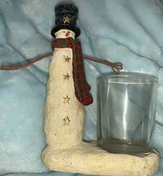 a snowman figurine next to a glass on a blue blanket with stars