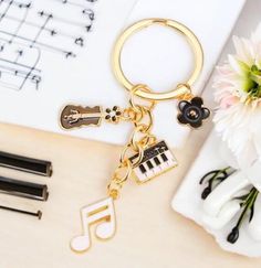 a keychain with musical notes and keys on it next to a flower vase