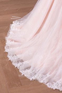 a wedding dress with white lace on the bottom and pink tulle overlays