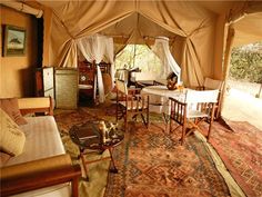 the inside of a tent with tables, chairs and couches on top of it