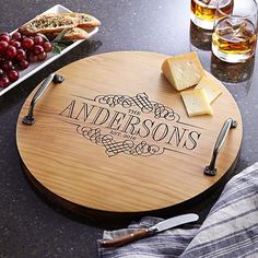 a personalized cutting board with cheese, grapes and wine on the table next to it