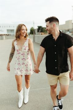 a man and woman walking down the street holding hands