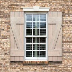 an open window with shutters on a brick building