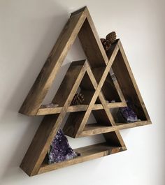 a wooden shelf with three pyramids and rocks on it's sides, hanging from the wall