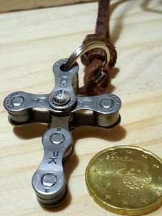 a small metal cross sitting on top of a wooden table next to a gold coin