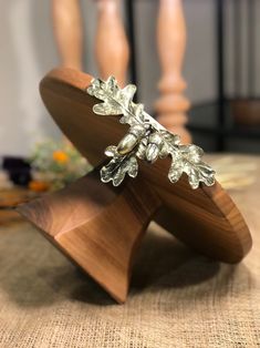 a close up of a wooden stand with metal leaves on it's top and bottom