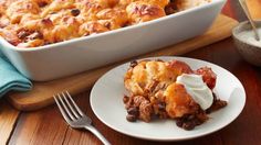 a white plate topped with food next to a casserole covered in sour cream