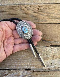 Handsome Turquoise bolo tie...1 15/16" tall by 1 1/2" wide at the widest spot, handmade and signed in sterling silver 925 by a Navajo silversmith with a beautiful Golden Hills turquoise stone that I cut...the cord is a 5mm wide 48" long braided black leather and the bolo tips are handmade also in sterling silver 925.. the bolo has gorgeous stamping!! Artisan Hand-tooled Jewelry For Rodeo, Western Style Concho Jewelry As Gift, Western Style Concho Jewelry For Gift, Artisan Lariat Jewelry For Rodeo, Blue Turquoise Concho Necklace As A Gift, Handmade Artisan Jewelry For Rodeo, Vintage Silver Jewelry For Rodeo, Western Engraved Jewelry For Rodeo, Western Style Engraved Jewelry For Rodeo