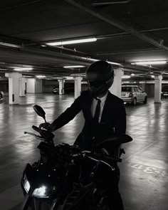 a man in a suit and tie standing next to a motorcycle parked in a parking garage