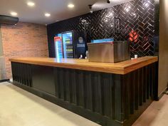 the front desk of a restaurant with brick walls and black tiles on the back wall