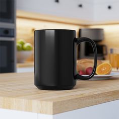 a black coffee mug sitting on top of a wooden counter next to an orange slice